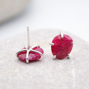 Peut inclure: Une paire de boucles d'oreilles en argent avec une pierre précieuse de rubis rouge vif dans chacune. Le rubis est serti dans une monture à quatre griffes.