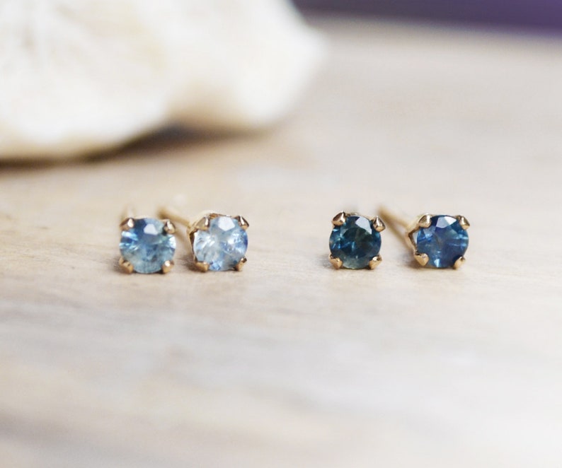 Puede incluir: Un par de pendientes de oro con piedras preciosas azules. Los pendientes est&aacute;n engastados con piedras preciosas redondas y facetadas. Las piedras preciosas son de un azul m&aacute;s claro a la izquierda y de un azul m&aacute;s oscuro a la derecha.