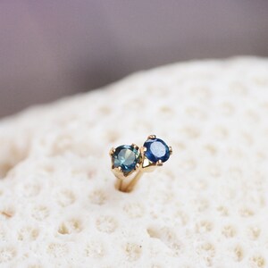Puede incluir: Un par de pendientes de oro con piedras preciosas azules. Los pendientes est&aacute;n engastados con dos piedras redondas, una ligeramente m&aacute;s grande que la otra.