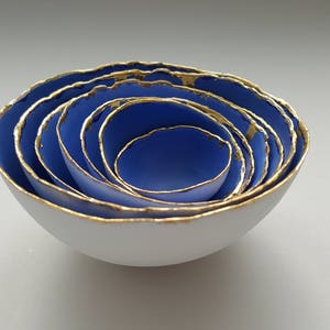 Set of 7 small stoneware fine bone china nesting bowls in blue and white with real gold finish.