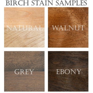 May include: Four wood stain samples on birch wood. The samples are labelled "Natural", "Walnut", "Grey", and "Ebony".
