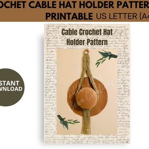 May include: Printable crochet pattern for a cable hat holder. The pattern features a brown hat hanging from a crocheted cable with a beige background and handwritten text.