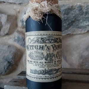 May include: A black glass bottle with a cork stopper and a white label that reads "Witch's Pow", "Full Strength Magick Properties Guarantee", "For Use With All Manner of Spells", "Dissolve the contents of one of these in a cup of cold tea and drink before casting", "Caution - liquid is flammable", "Bedlam & Johnson", "13 High Street - Back Door - Sandwich".