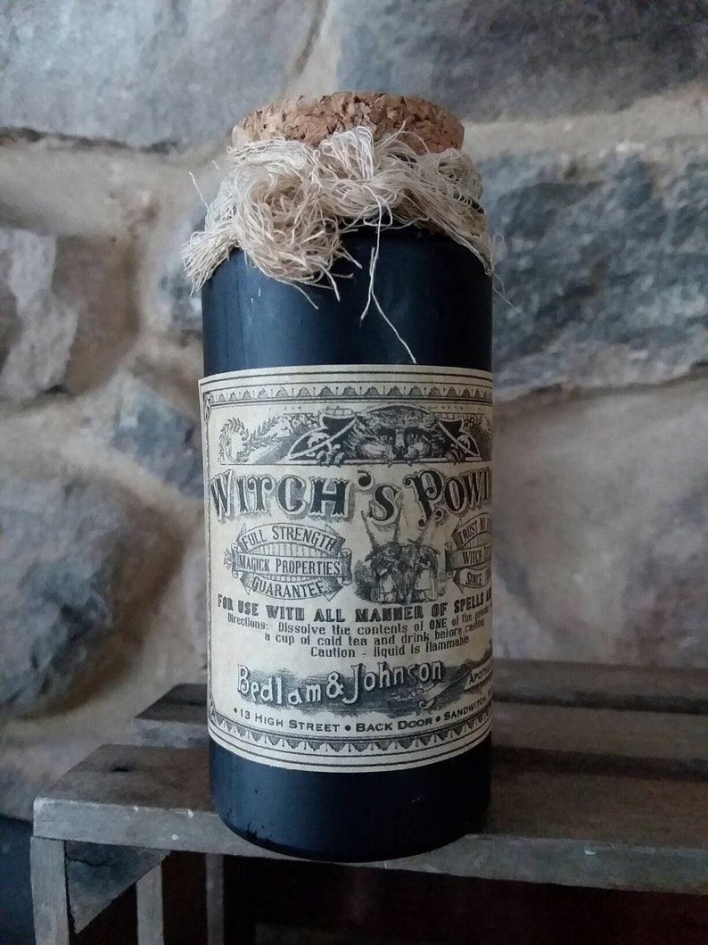 May include: A black glass bottle with a cork stopper and a white label that reads "Witch's Pow", "Full Strength Magick Properties Guarantee", "For Use With All Manner of Spells", "Dissolve the contents of one of these in a cup of cold tea and drink before casting", "Caution - liquid is flammable", "Bedlam & Johnson", "13 High Street - Back Door - Sandwich".