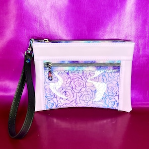 May include: A lavender-colored zippered pouch with a clear plastic front panel featuring a floral design. The pouch has a black strap.