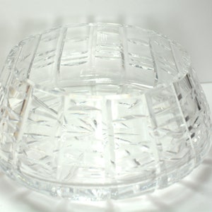 May include: A clear glass bowl with a cut crystal design. The bowl has a wide, shallow base and a flared rim.