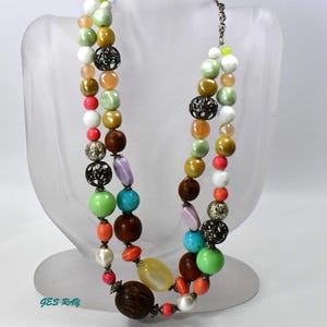 May include: A multi-strand necklace with colorful beads, including turquoise, green, pink, orange, and brown. The necklace features metal accents and a variety of bead shapes and sizes.