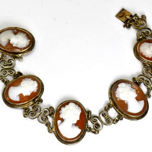 Peut inclure: Un bracelet vintage &agrave; cam&eacute;es avec six cam&eacute;es ovales, chacun pr&eacute;sentant un profil blanc dans des cadres dor&eacute;s. Le bracelet est reli&eacute; par des maillons en filigrane et poss&egrave;de un fermoir. Un bijou classique.