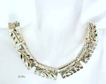 May include: A gold-tone necklace with a leaf design. The necklace is made of metal and has a chain link style. The leaves are cut out and have a delicate design.
