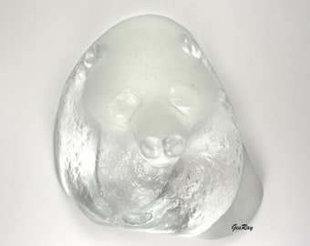 May include: A clear glass sculpture of a panda bear with a textured surface. The sculpture is in a sleeping position with its head resting on its paws.