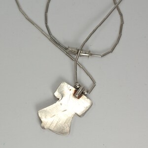 Peut inclure: Un collier en argent avec un pendentif en argent en forme de personne. Le pendentif est attach&eacute; &agrave; la cha&icirc;ne par un petit anneau en argent.