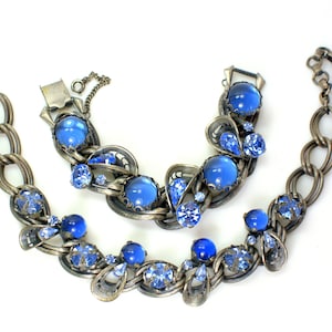 May include: A vintage blue rhinestone necklace and bracelet set. The necklace and bracelet feature a delicate chain with large blue cabochon stones and smaller blue rhinestones.
