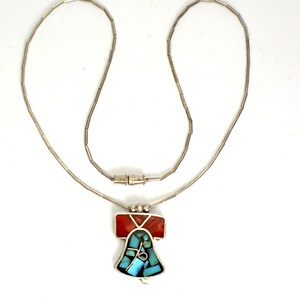 Peut inclure: Un collier en argent avec un pendentif en forme de cloche en turquoise et pierres rouges.