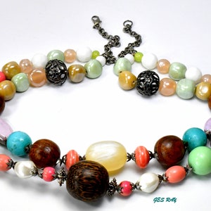 May include: A multi-strand necklace with a variety of colorful beads, including turquoise, pink, green, brown, and white. The necklace features metal accents and a large wooden bead.