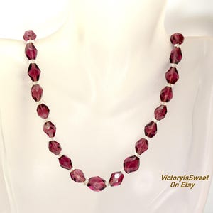 May include: A necklace with faceted, deep purple beads and smaller, clear beads. The necklace is displayed on a white mannequin. The Etsy shop name "VictorylsSweet On Etsy" is visible in the lower right corner.