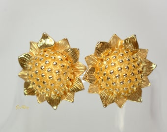 May include: A pair of gold-tone sunflower earrings. The earrings are made of metal and have a textured surface. The sunflowers are detailed with petals and a centre.