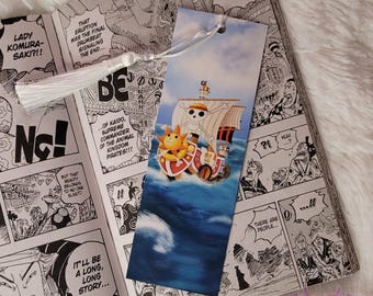 May include: A blue and white bookmark featuring a cartoon image of a pirate ship with a yellow and white character on the deck. The text "I am not Kaido!" is printed on the bookmark.
