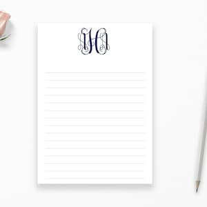 May include: A white notepad with blue lined paper and a navy blue monogram of the letters "HH" in a decorative script font.