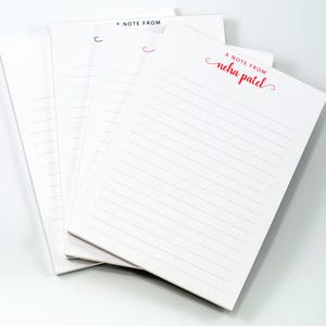 a stack of white lined notepads with the text "A Note From" printed on them.