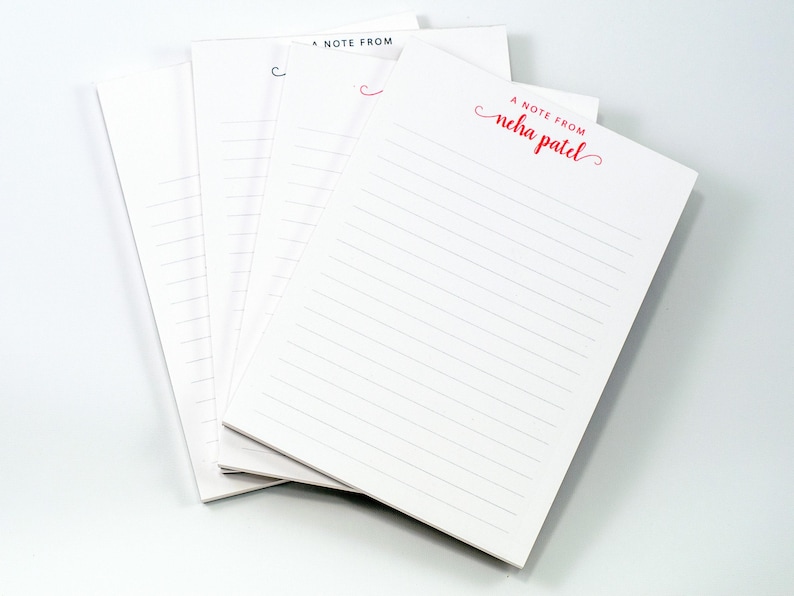 a stack of white lined notepads with the text "A Note From" printed on them.