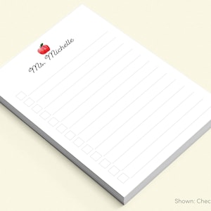 May include: White notepad with a red apple and the text "Ms. Michelle" at the top. The notepad has lined paper and a checklist.