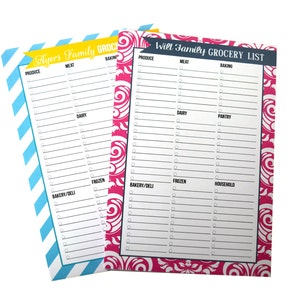 May include: Two rectangular grocery list notepads with checkboxes and category headers. The left notepad features a blue and white diagonal stripe border with a yellow banner reading Ayers Family GROCERY. The right notepad has a pink and white floral damask border with a dark banner reading Witt Family GROCERY LIST.