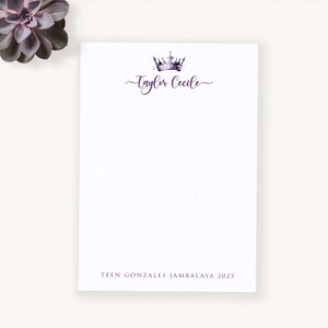 May include: White stationery with a purple watercolor crown and the name "Taylor Cecile" in a script font. The text "TEEN GONZALES JAMBALAYA 2025" is printed at the bottom. A succulent plant is in the upper left corner.