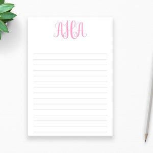 May include: A white notepad with pink lined paper and a pink monogram "AHA" at the top.