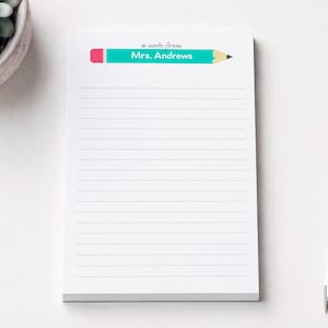 May include: White notepad with horizontal lines, featuring a teal pencil graphic and the text "a note from Mrs. Andrews." A white pen with a silver tip rests beside the notepad. A succulent plant in a gray pot is in the upper left corner.