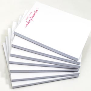 A stack of white sticky notes with red text on them.