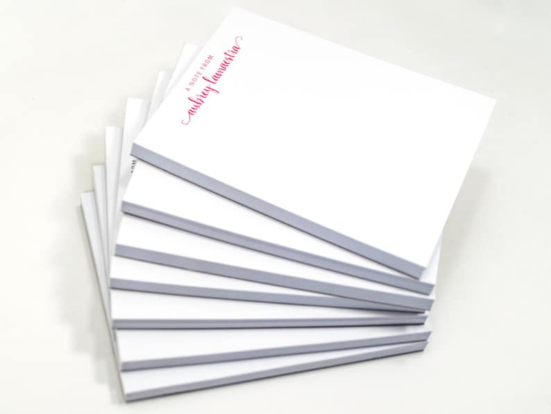 A stack of white sticky notes with red text on them.