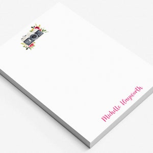 May include: White notepad with a vintage camera and floral design. The notepad has the name "Michelle Hayworth" printed in pink at the bottom.