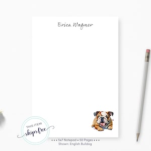May include: Personalized notepad with a white background and the name "Erica Wagner" at the top. The notepad features a cartoon illustration of a brown and white English Bulldog with a pink tongue sticking out. The notepad is 5x7 inches and has 50 pages.
