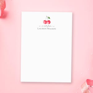 May include: White notepad with a cherry illustration and the text "a note from LAUREN WILSON".