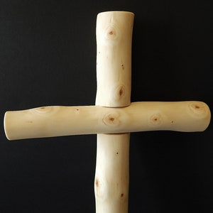 Puede incluir: Una cruz de madera hecha de ramas naturales con un color marr&oacute;n claro y una textura nudosa.