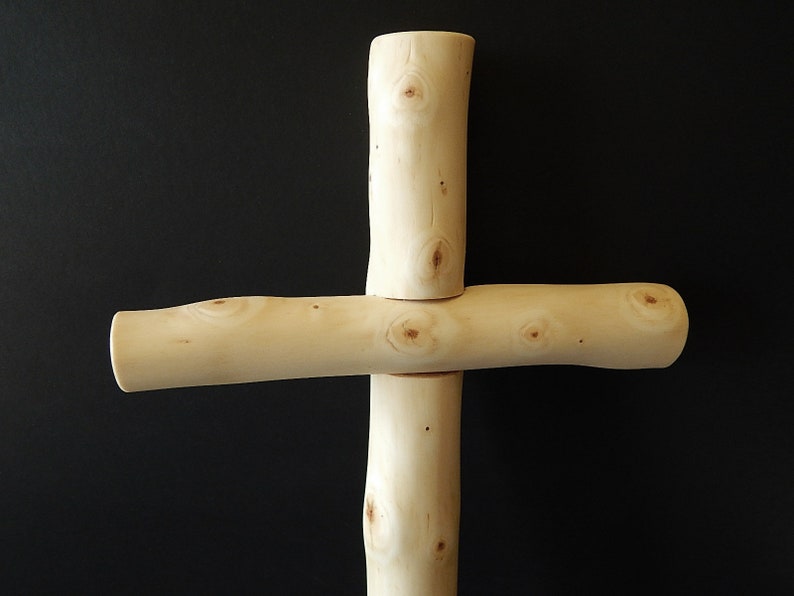 Puede incluir: Una cruz de madera hecha de ramas naturales con un color marr&oacute;n claro y una textura nudosa.