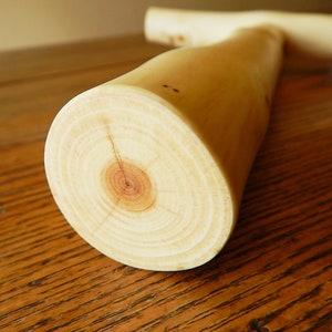 Puede incluir: Primer plano de una clavija de madera marr&oacute;n claro con un patr&oacute;n de veta visible y un nudo marr&oacute;n claro en el centro.