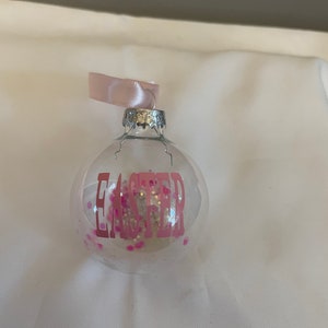 May include: A clear glass ornament with pink glitter and the word "Easter" in pink lettering.