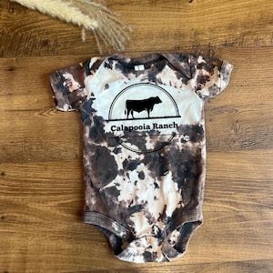 Body de bebé de piel de vaca estilo rancho personalizado, body campestre, regalo de baby shower de vaquero con temática country western, teñido anudado inverso blanqueado a mano.