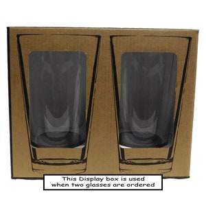 May include: A brown cardboard box containing two clear glass tumblers. The box has the text "This Display box is used when two glasses are ordered" printed on the bottom.