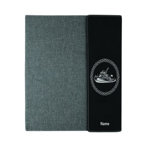 May include: A gray and black fabric binder with a white tugboat design on the front. The binder has a black leather-like flap with the word "Name" printed on it.
