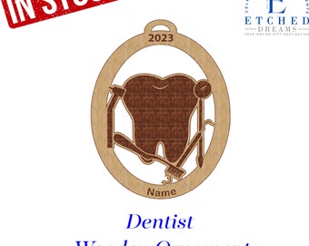 May include: A brown wooden ornament shaped like a tooth with dental tools, a toothbrush, and the year 2023. The ornament says "Dentist Wooden Ornament" and "Name" at the bottom.