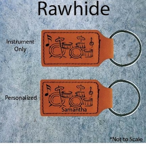 May include: Two orange leather keychains with a drum set design and a metal ring. One keychain says "Instrument Only" and the other says "Personalized" with the name "Samantha". The word "Rawhide" is at the top.