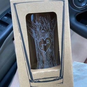 May include: A clear glass with a tree design etched into the side. The tree has a heart carved into it with the initials "J+R" inside the heart.