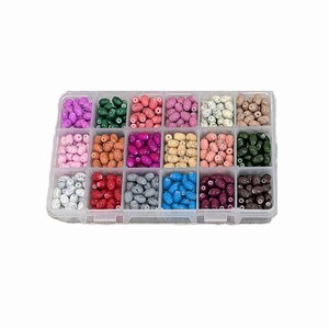 May include: A clear plastic organizer filled with oval-shaped beads in various colors, including pink, green, orange, and blue. The beads are arranged in individual compartments, offering a diverse selection for crafting and jewelry making.