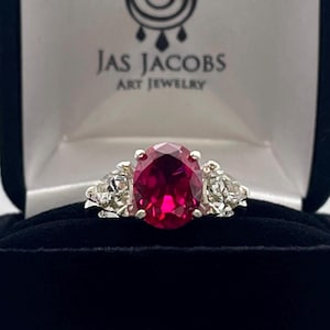 4.5ctw Oval Cut Ruby Ring: Trillion White Sapphire Accents, Sterling Silver with Sizing