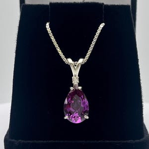 May include: A pear-shaped purple gemstone pendant necklace with small diamond accents on a silver chain.