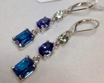 May include: A pair of silver dangle earrings with blue and green gemstones. The earrings are from the brand "J.A.S. JACOBS Art Jewelry".