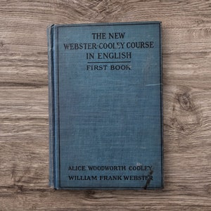 May include: A blue book titled "The New Webster-Cooley Course in English First Book" by Alice Woodworth Cooley and William Frank Webster.