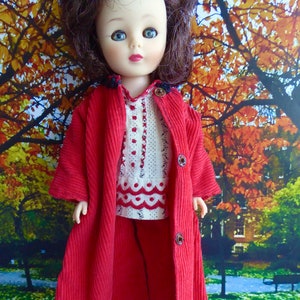 May include: A red corduroy coat with a white and red patterned blouse and matching trousers. The doll has brown hair and blue eyes.